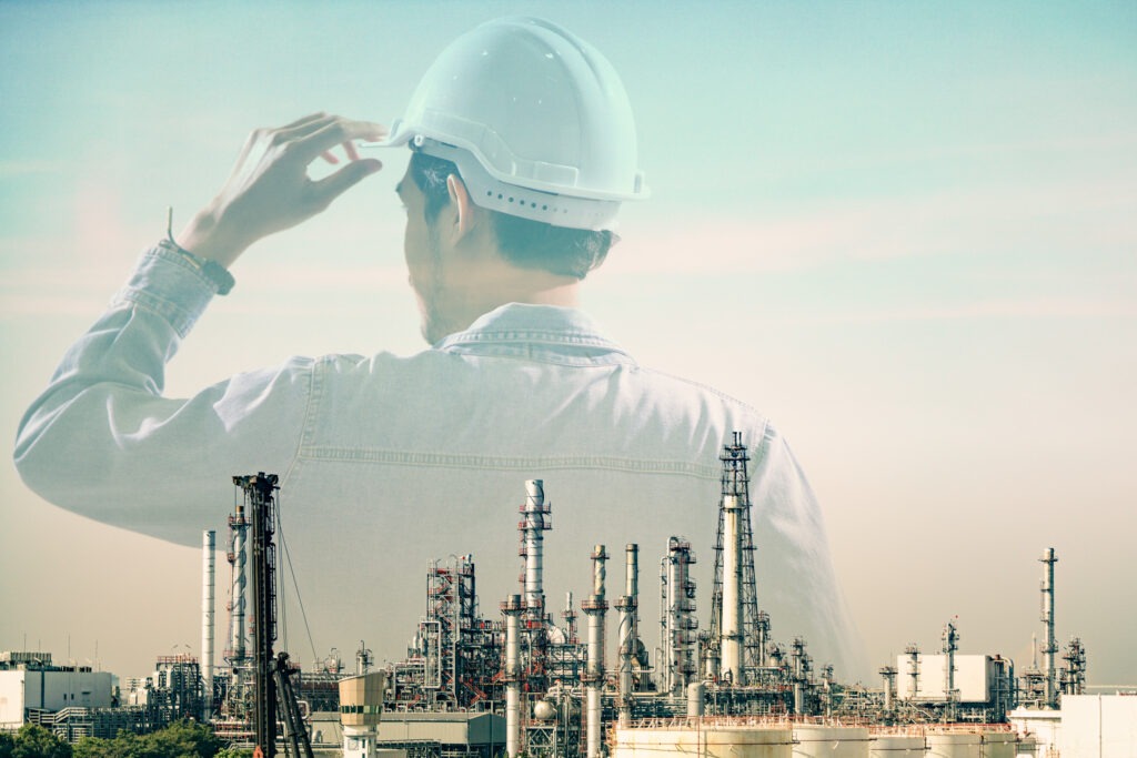 Double Exposure of Behind Engineer Wearing Helmet Safety with Blurred Oil Refinery Plant as a Background